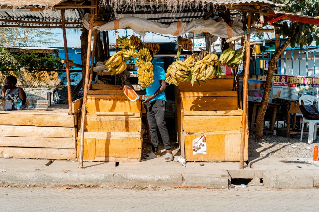 A fruit seller slicing watermelon at a banana stall in Arusha