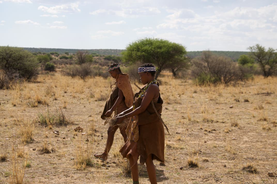 Two Hadzabe women foraging across the dry bush near Lake Eyasi
