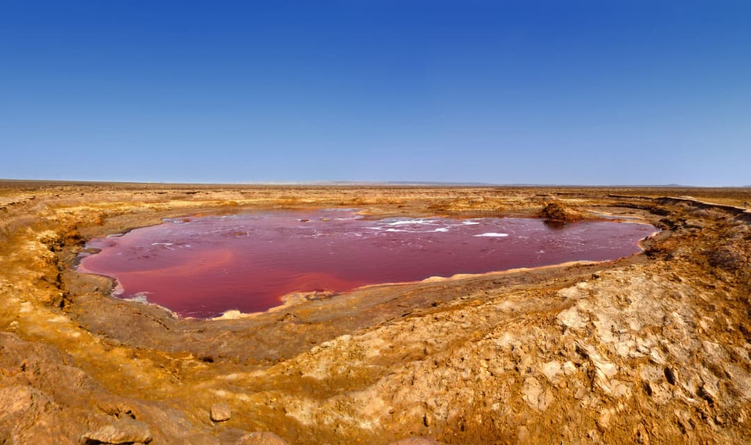 The red alkaline waters of Lake Natron under a deep blue sky