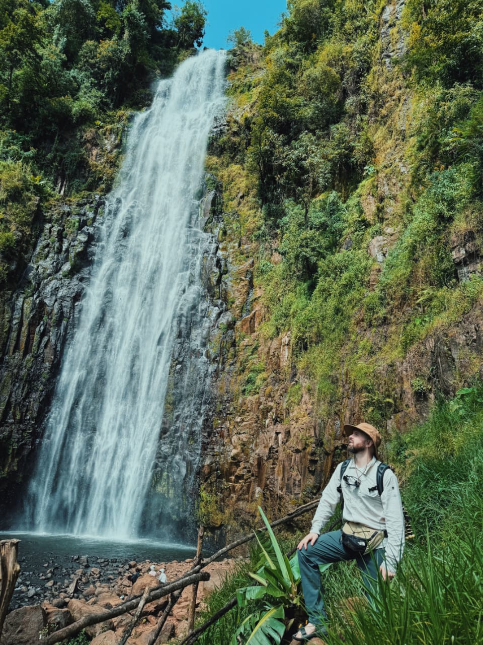 A hiker looking up at Materuni Waterfall
